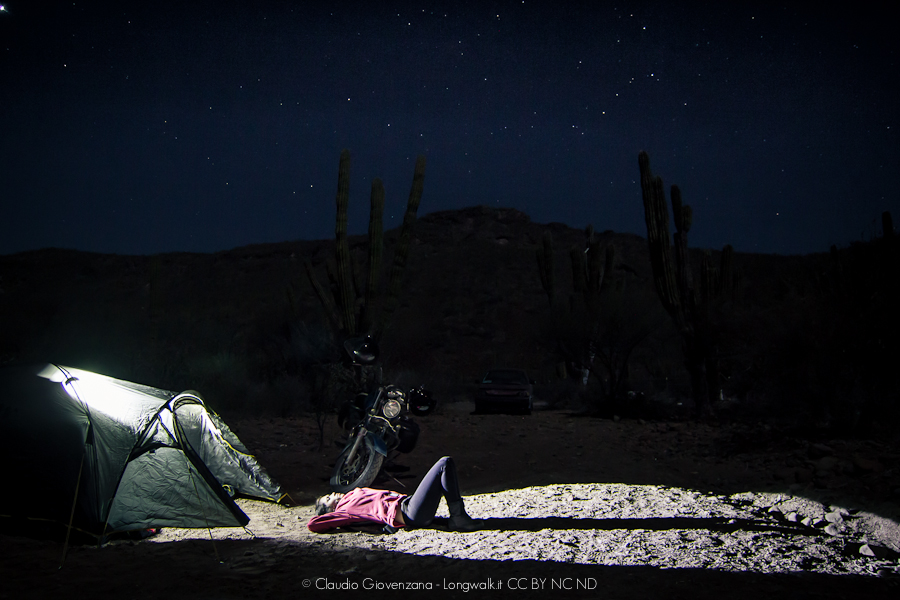 Accampamento in tenda nella Bassa California, la motoguzzi e una ragazza sotto le stelle.