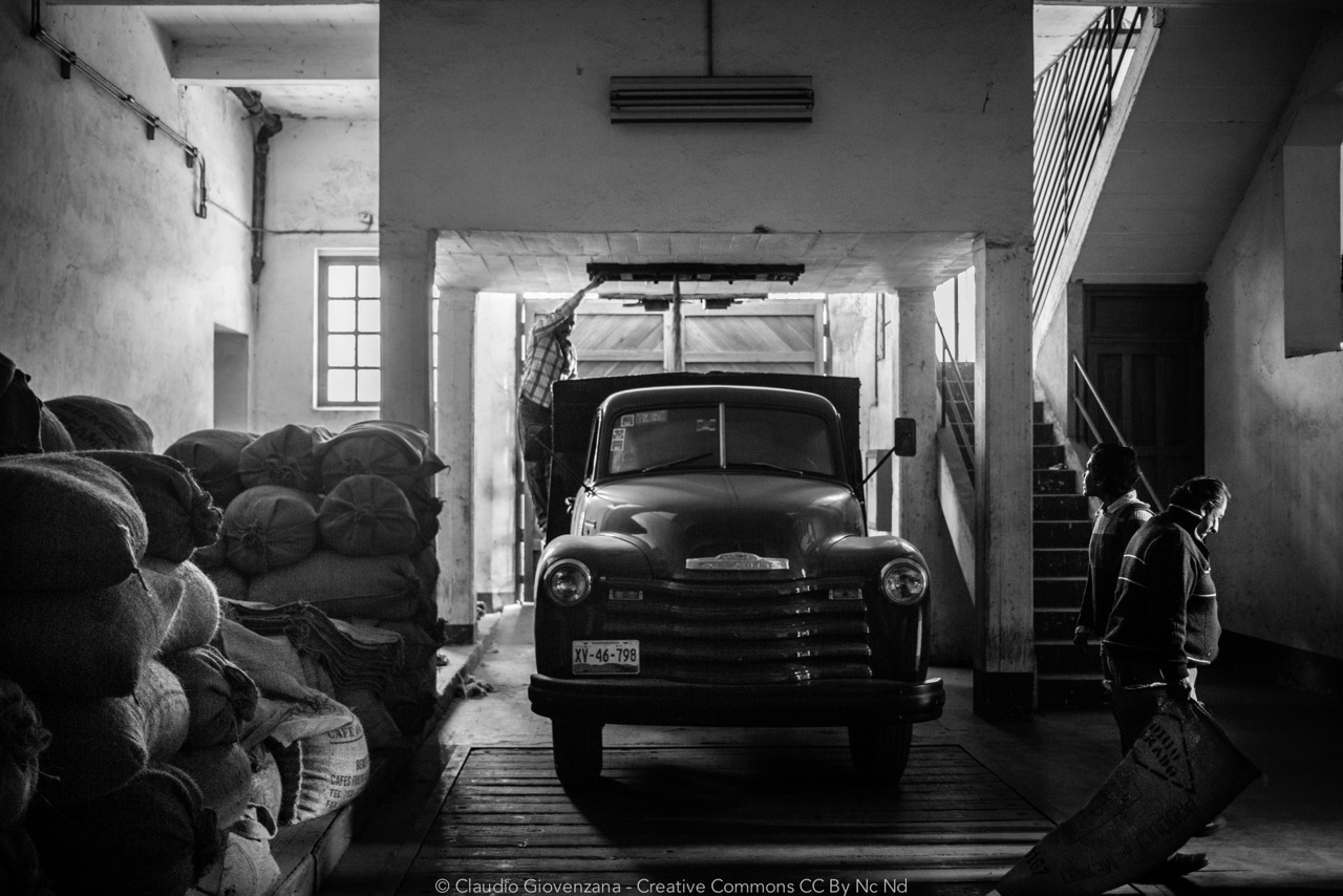una fabbrica che processa caffe in Messico con un vecchio furgone sacchi di iuta e varie persone